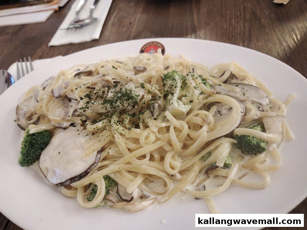 A creamy pasta dish with mushrooms, broccoli, and herbs on a white plate.