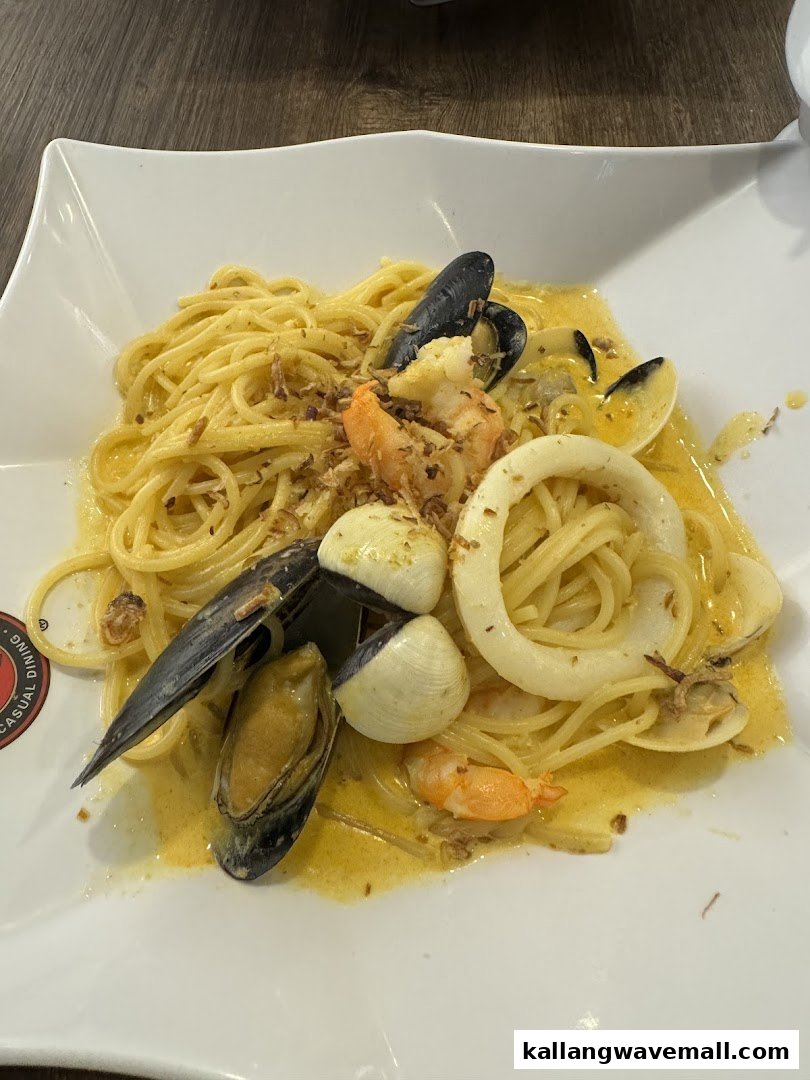 A close-up of a delicious seafood pasta dish with mussels, clams, squid, and prawns in a creamy sauce.