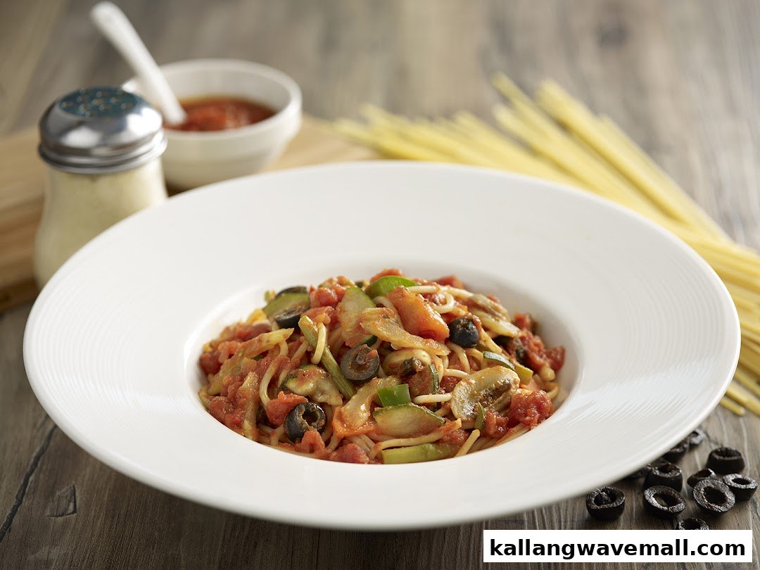 A vibrant plate of pasta with tomato sauce, vegetables, and olives, ready to be enjoyed.