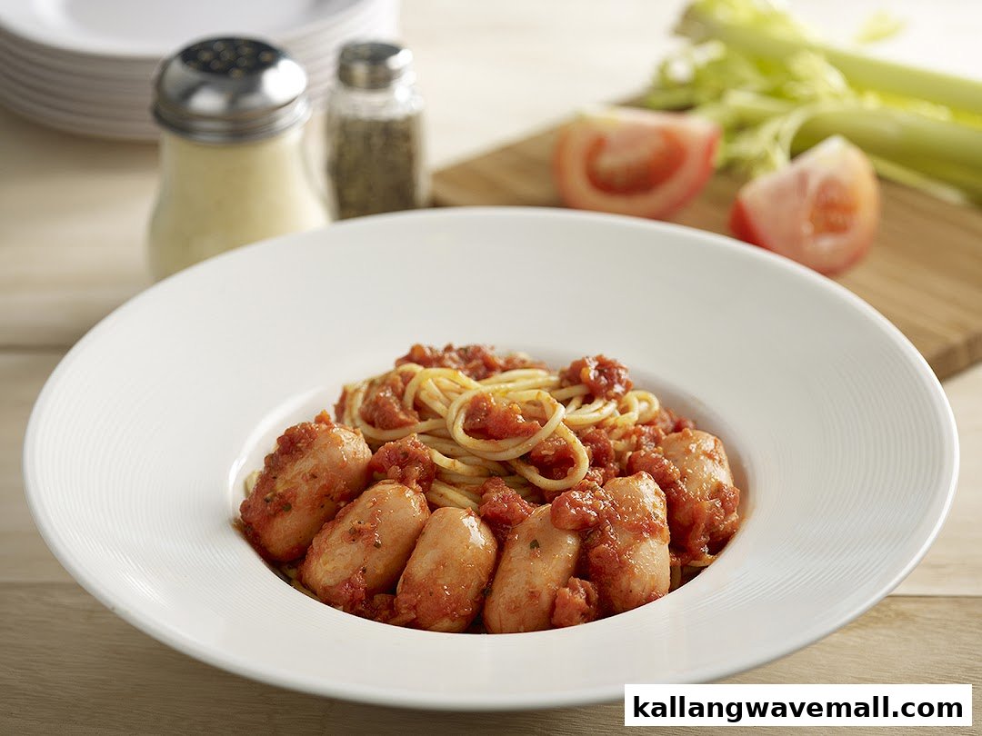 A close-up of spaghetti with tomato sauce and sausages in a white bowl.