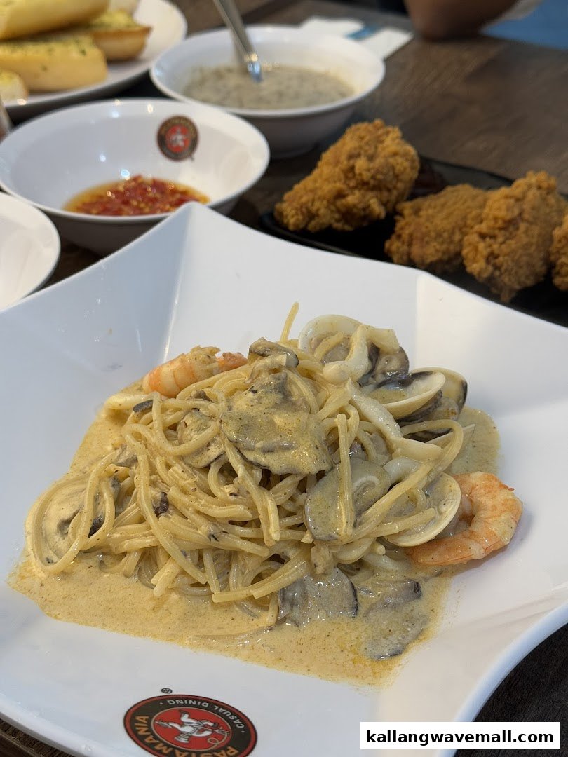 A close-up of creamy seafood pasta with mushrooms, alongside fried chicken and soup at PastaMania.