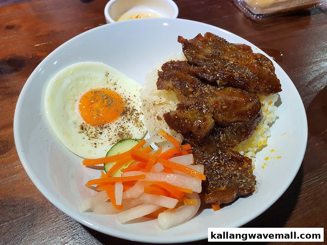 A delicious bowl of rice with grilled meat, a fried egg, and pickled vegetables.
