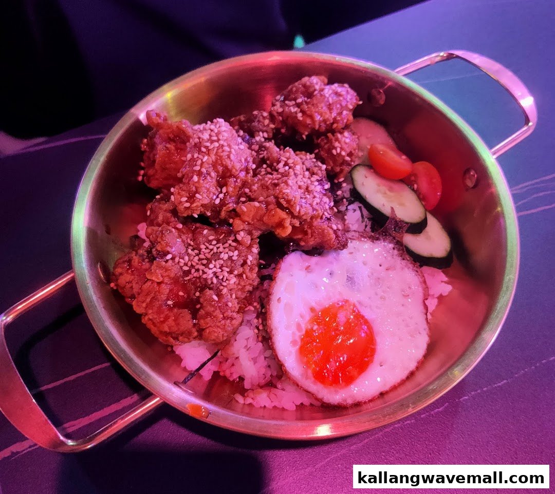 A delicious bowl of fried chicken with rice, a fried egg, and fresh vegetables.