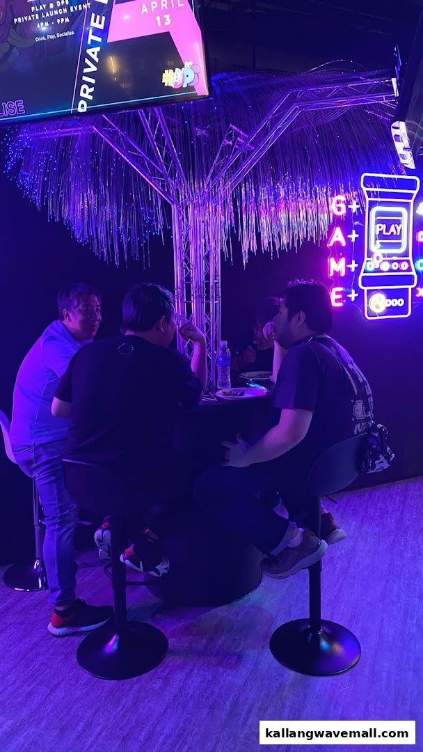 People gather around a table in a vibrant, neon-lit entertainment space with futuristic decor.