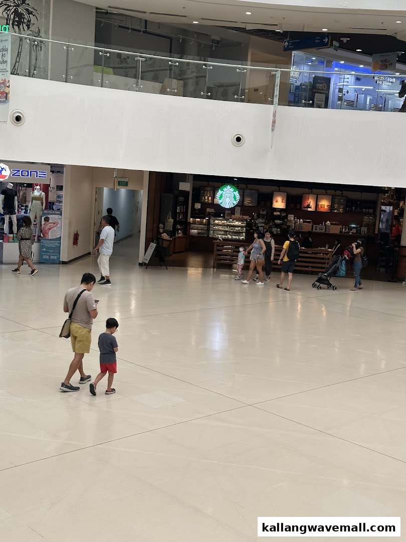 An interior view of a bustling shopping mall with various shops and people walking.