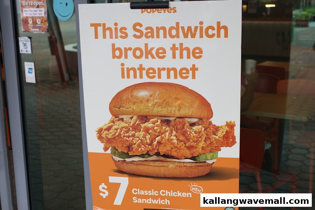 A promotional poster for Popeyes' Classic Chicken Sandwich displayed at the shop entrance.