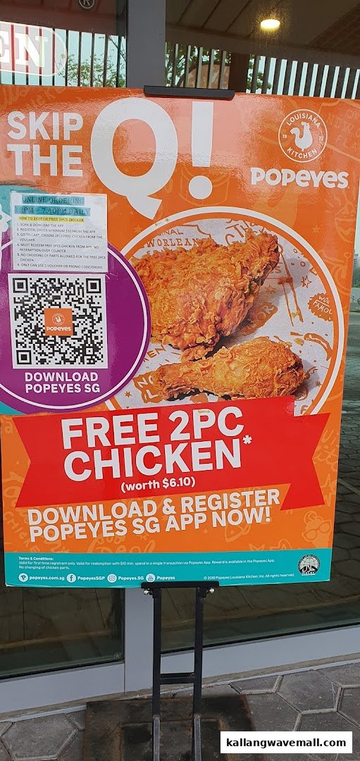 A Popeyes promotional standee advertising a free 2PC chicken offer for app download and registration.
