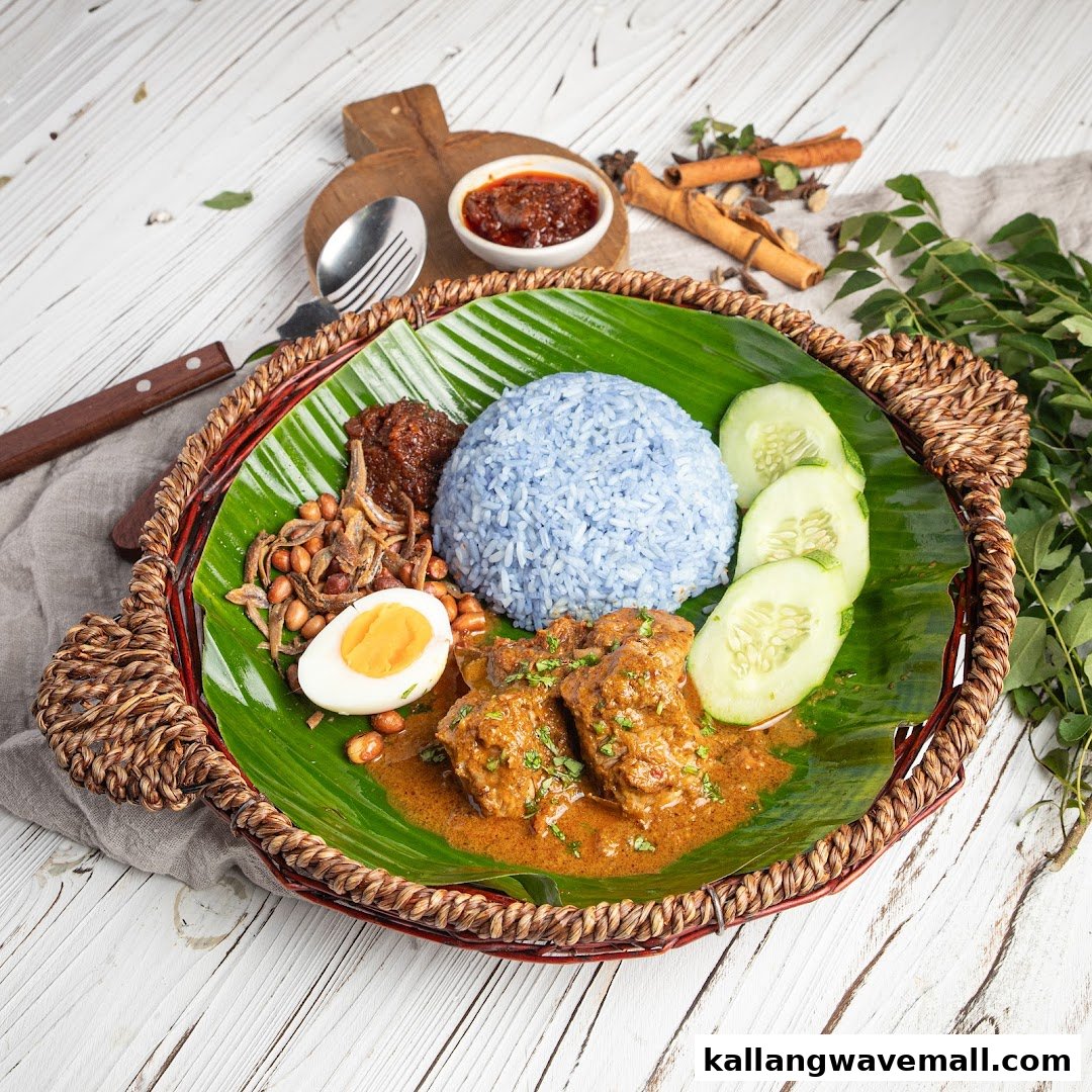 A vibrant Nasi Lemak dish featuring blue pea rice, chicken curry, anchovies, peanuts, egg, and cucumber.