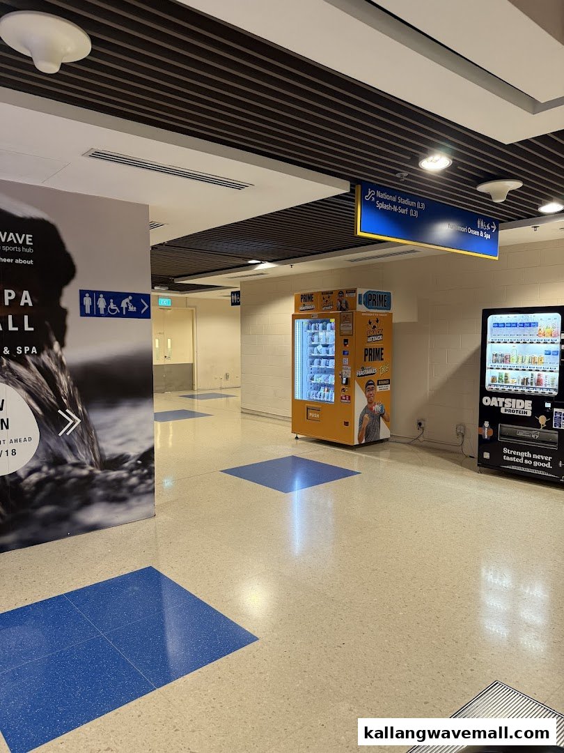 A brightly lit hallway featuring two vending machines and directional signs for various attractions.