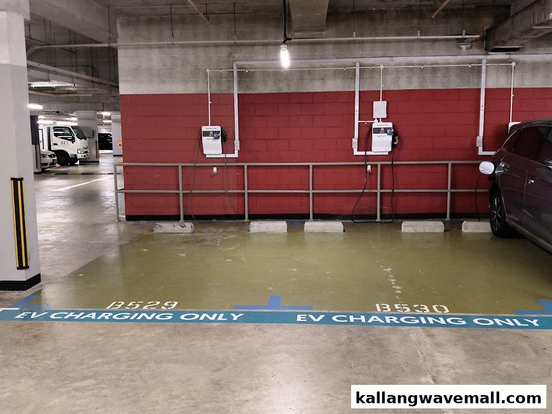 Two EV charging stations, one in use, located in a parking garage.