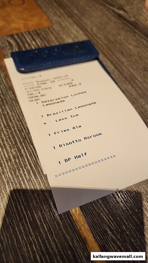 A close-up of a restaurant order chit displaying various food and drink items on a wooden table.