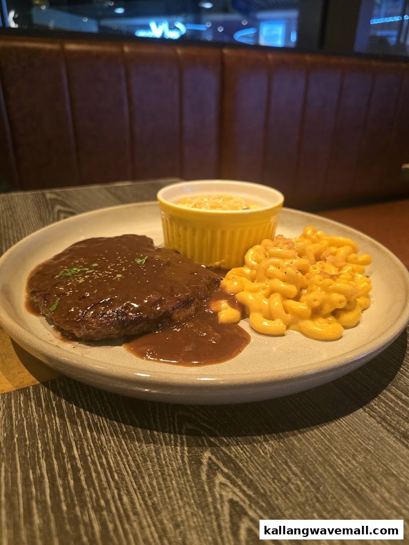 A delicious plate featuring a steak with gravy, macaroni and cheese, and a side dish.