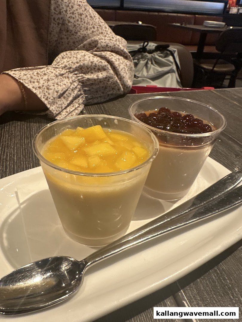 Two delightful desserts, one mango and one with dark pearls, served in cups on a white plate.