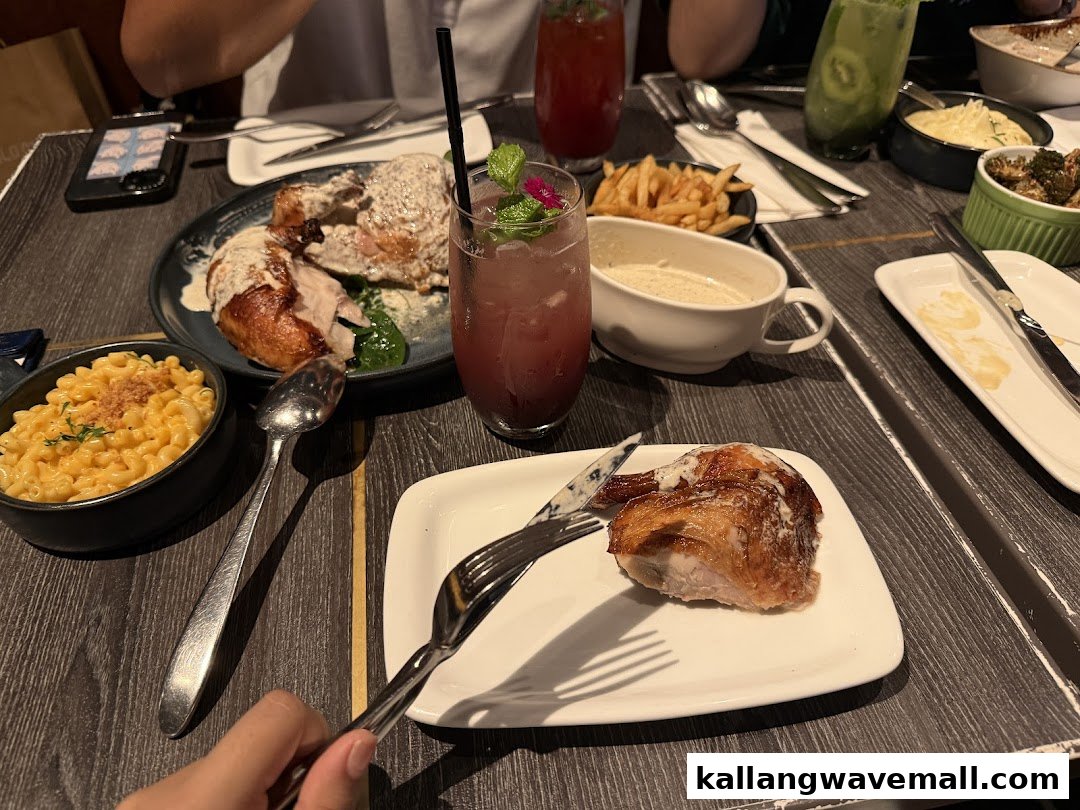 A table laden with delicious roasted chicken, mac and cheese, fries, and refreshing drinks at Poulet.