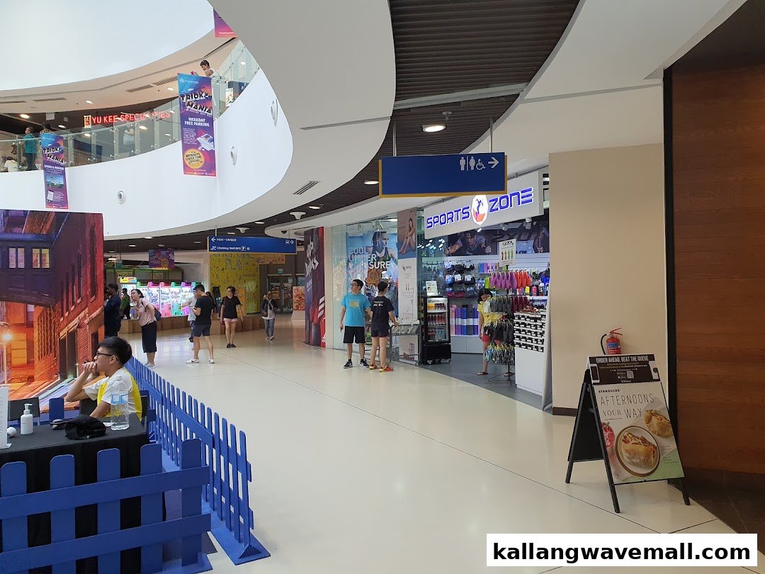 A vibrant shopping mall interior featuring multiple retail shops and active shoppers.