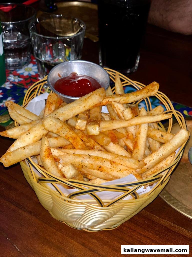 A basket of golden, seasoned french fries with a side of ketchup.