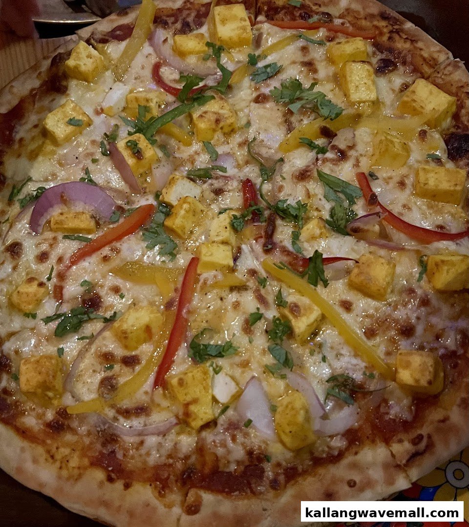 A delicious pizza topped with paneer, bell peppers, onions, and fresh cilantro.