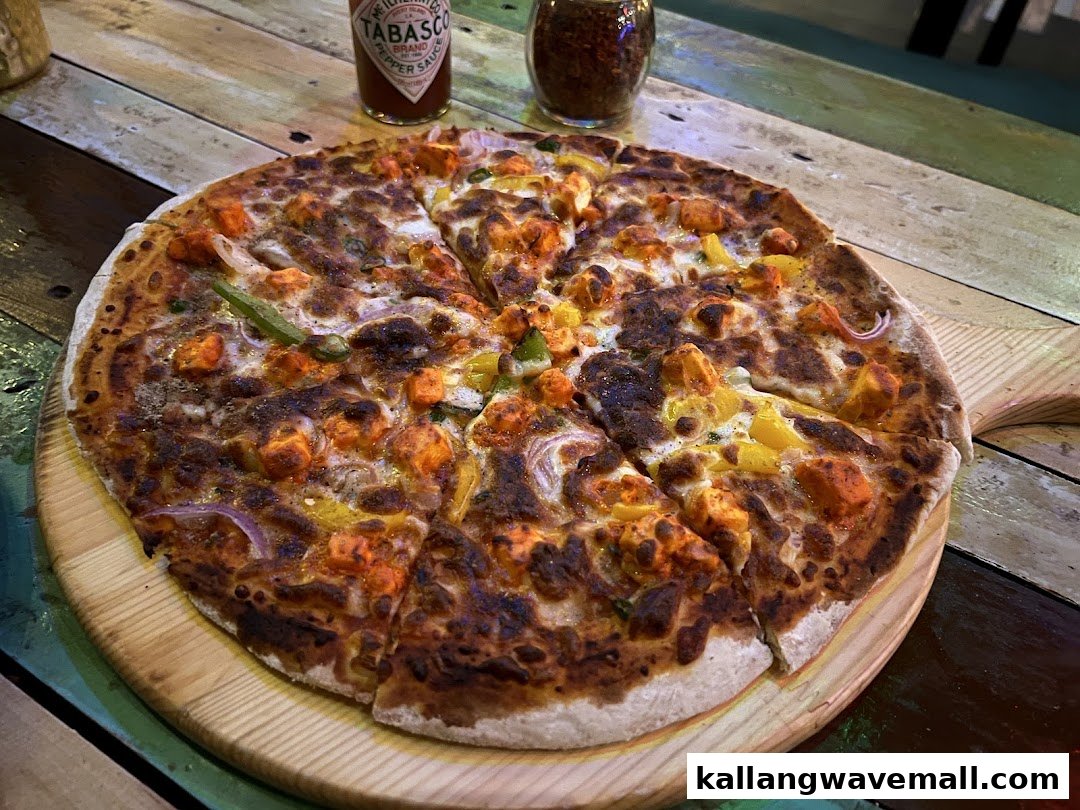 A delicious pizza with chicken, peppers, and onions on a wooden serving board.