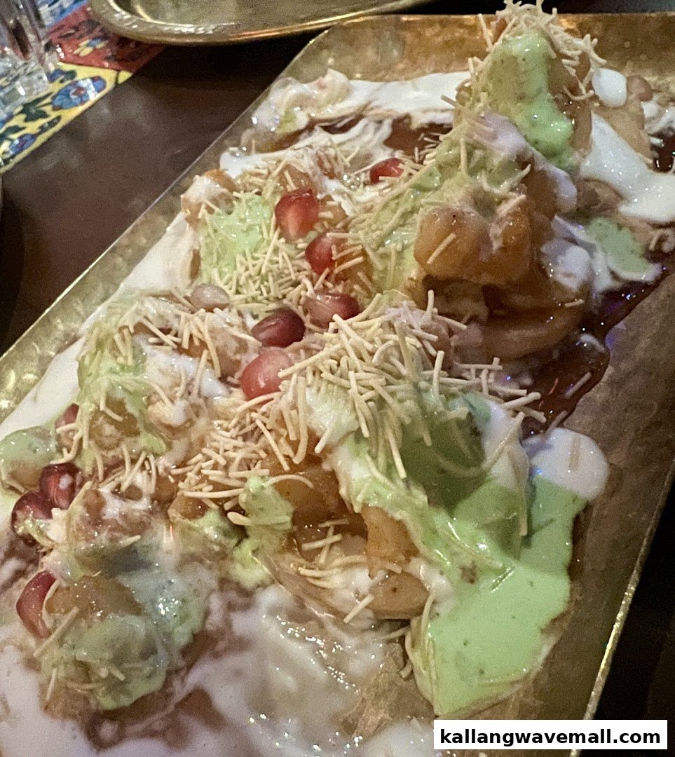 A vibrant close-up of a delicious Indian chaat dish, topped with sauces, pomegranate, and sev.