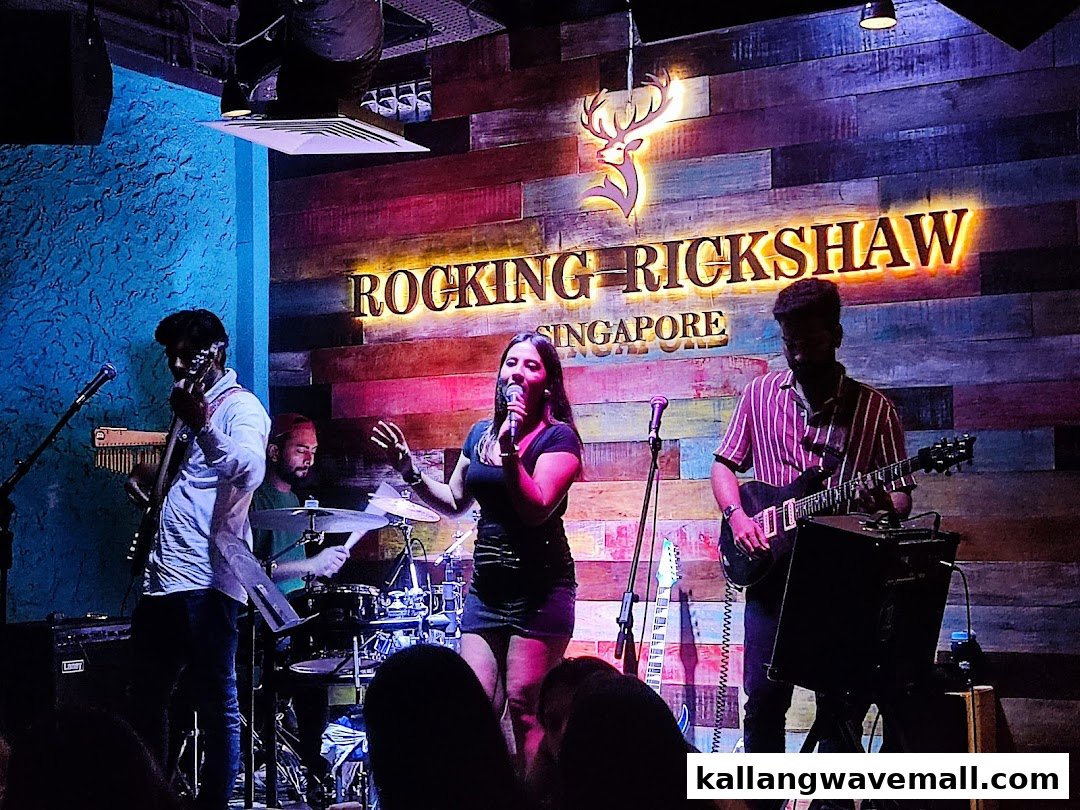 A live band performs on stage at Rocking Rickshaw, featuring a singer and musicians.