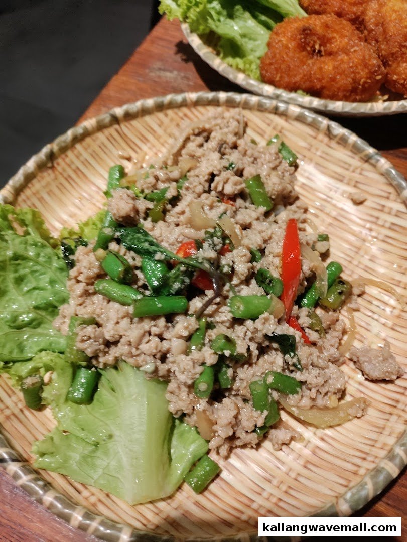 A close-up of a delicious Thai minced meat stir-fry with green beans and chili on a traditional woven plate.