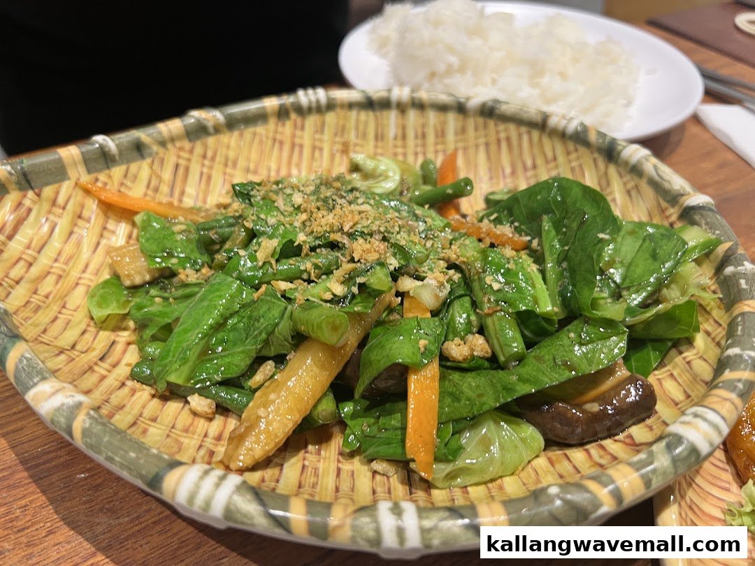 A vibrant plate of stir-fried greens and vegetables served in a traditional woven basket.