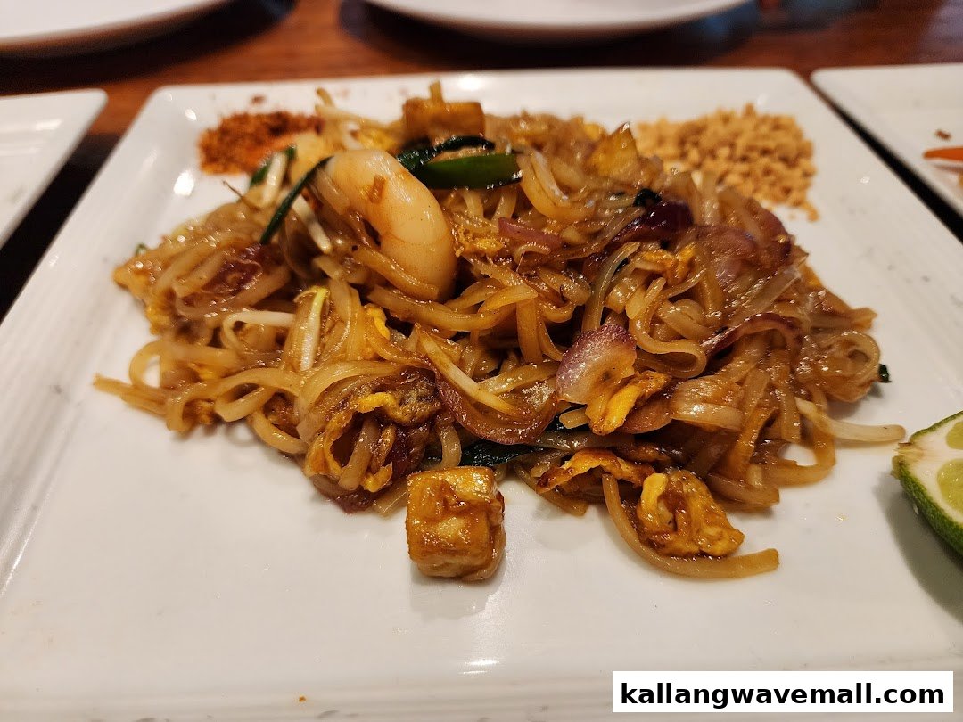 A delicious plate of Pad Thai with shrimp, tofu, and peanuts, served with a lime wedge.