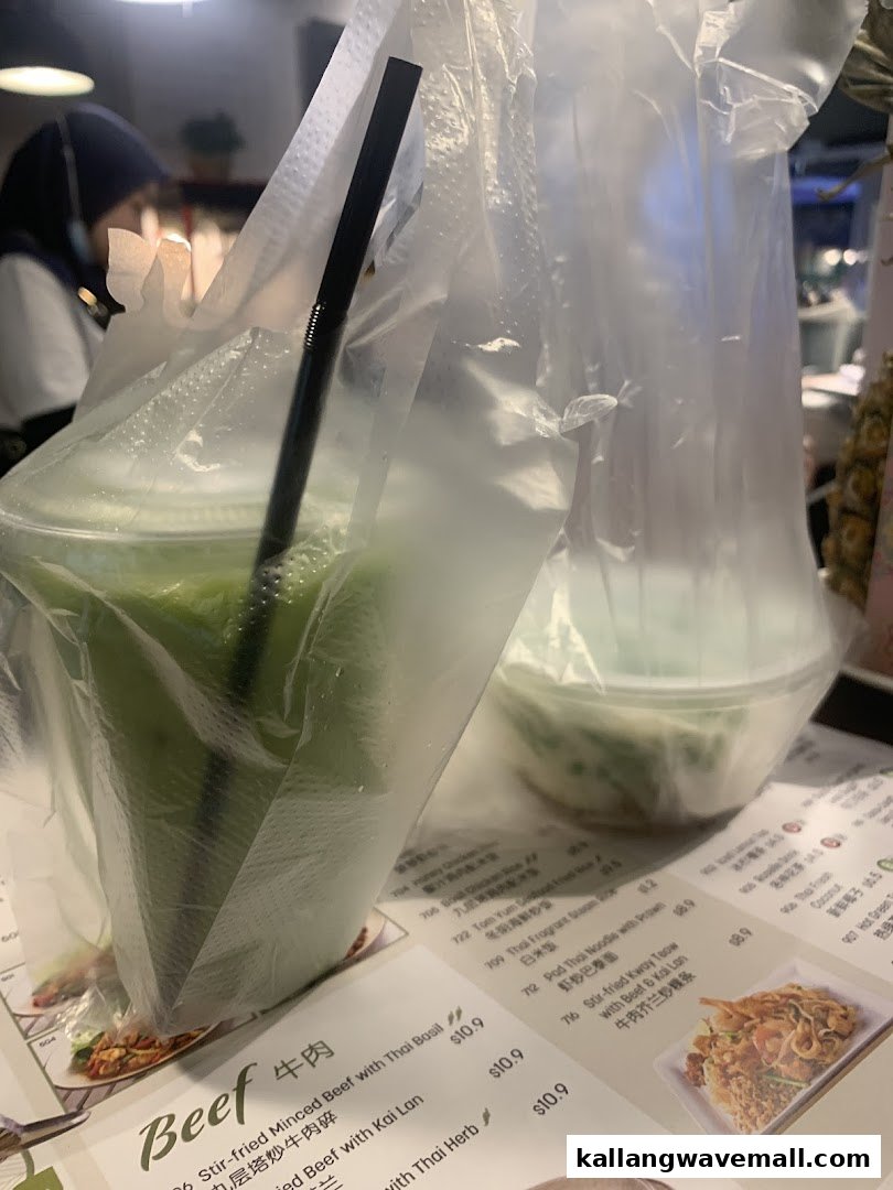 A refreshing green drink and a food item in plastic bags, with a menu visible in the foreground.