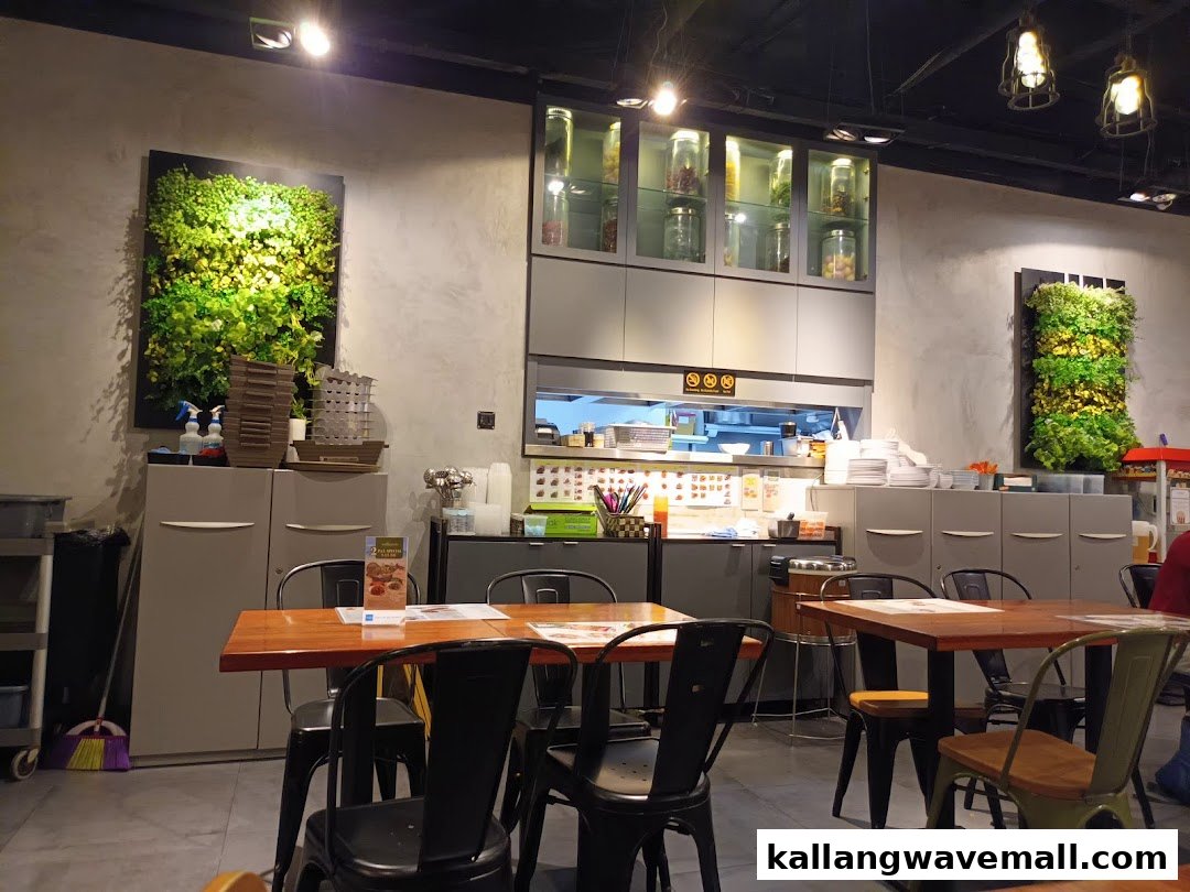 Interior view of Sanook Kitchen, featuring dining tables, an open kitchen, and green wall decor.