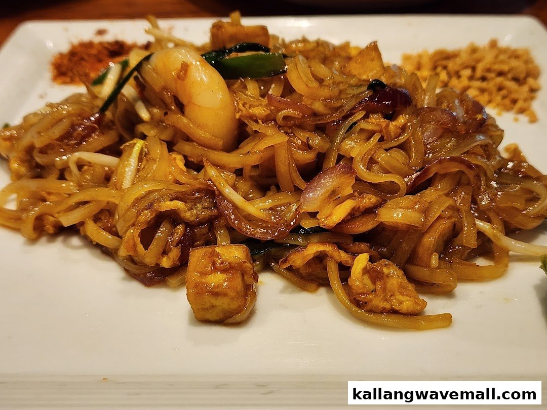 A close-up of a delicious plate of stir-fried noodles with shrimp, tofu, and vegetables.