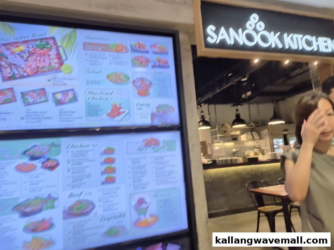 A digital menu display showcasing various Thai dishes at Sanook Kitchen, with the shop entrance visible.