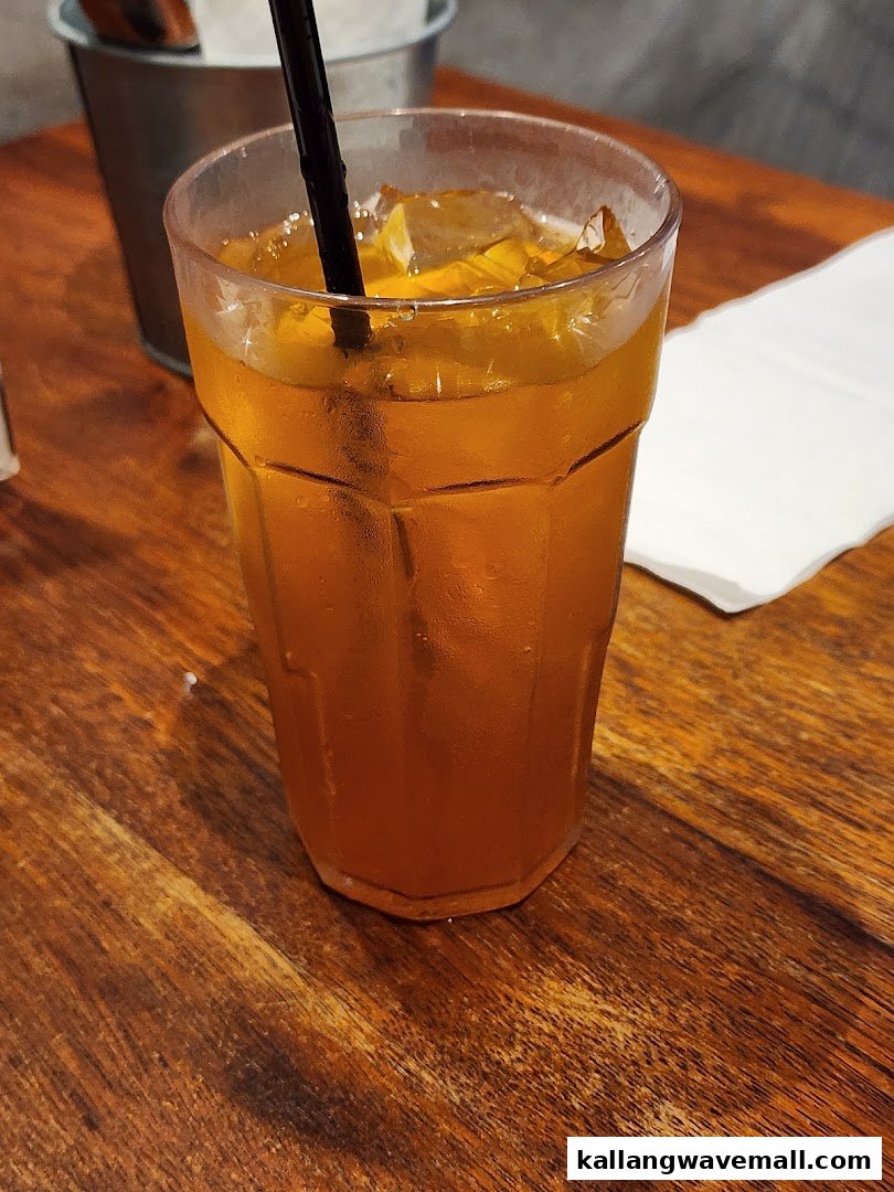 A refreshing iced drink with a straw on a rustic wooden table.
