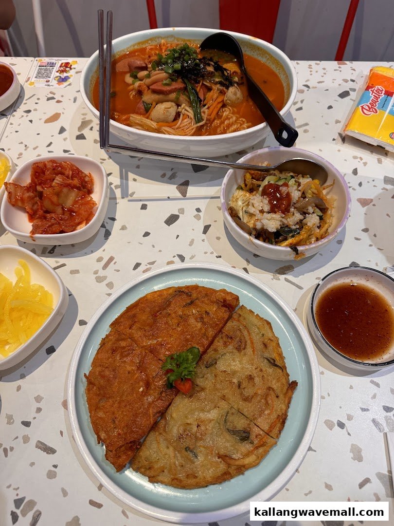 A vibrant spread of Korean dishes including a large hotpot, savory pancakes, and kimchi.