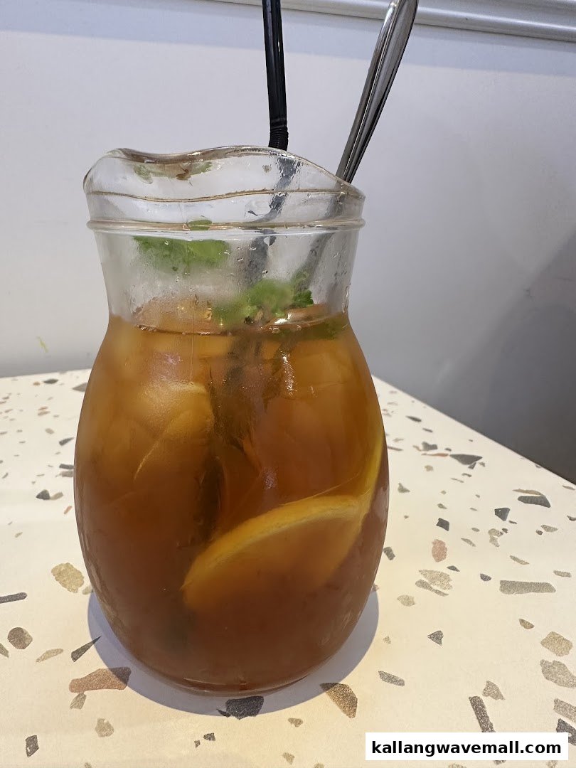 A pitcher of iced tea with lemon and mint on a speckled table.