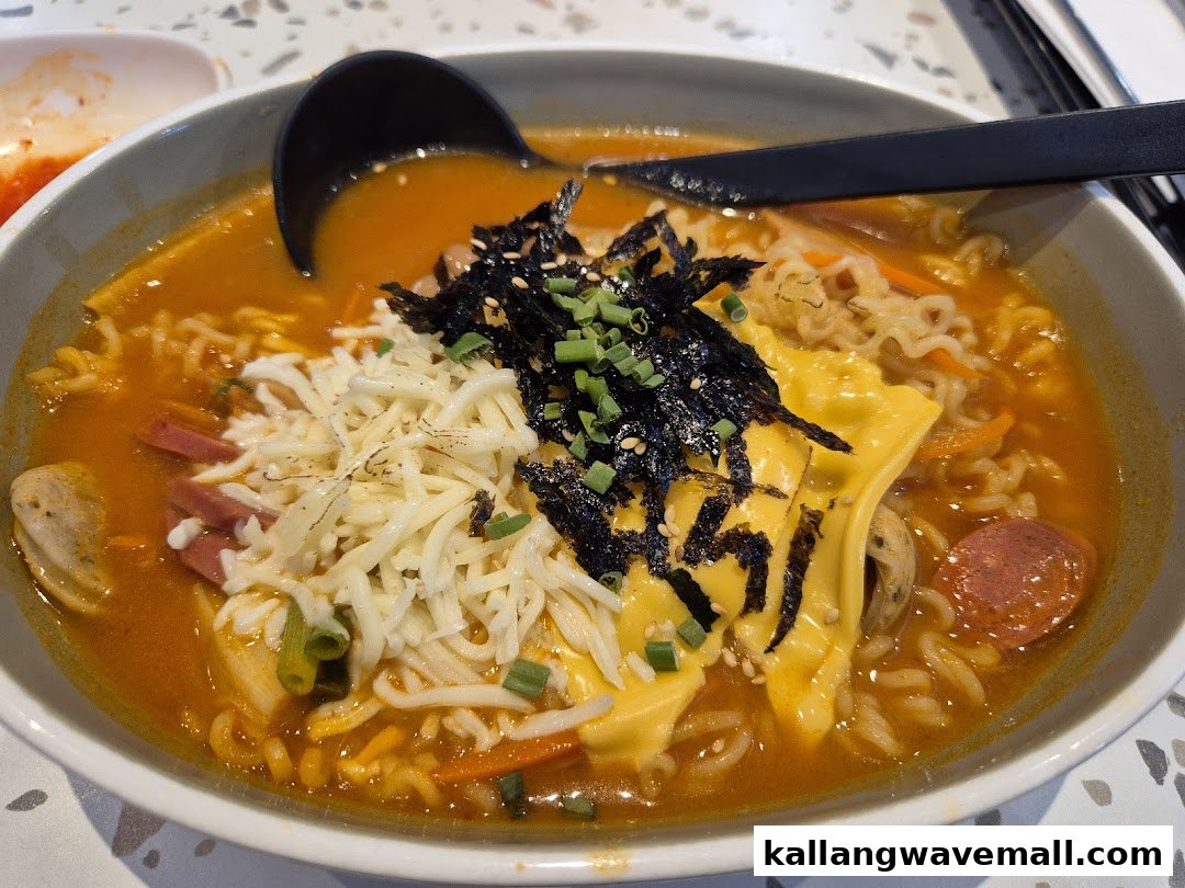 A vibrant bowl of Korean ramen with cheese, seaweed, and spring onions.