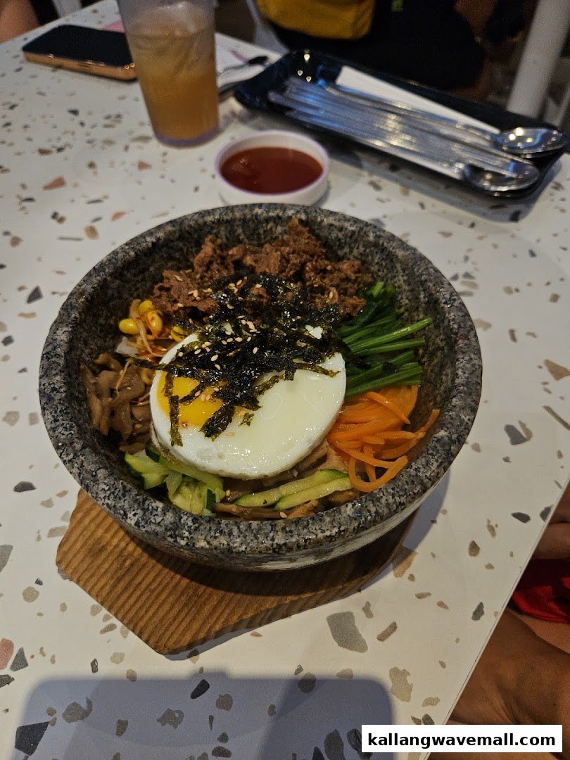 A vibrant Korean bibimbap dish with a fried egg and various toppings in a hot stone bowl.