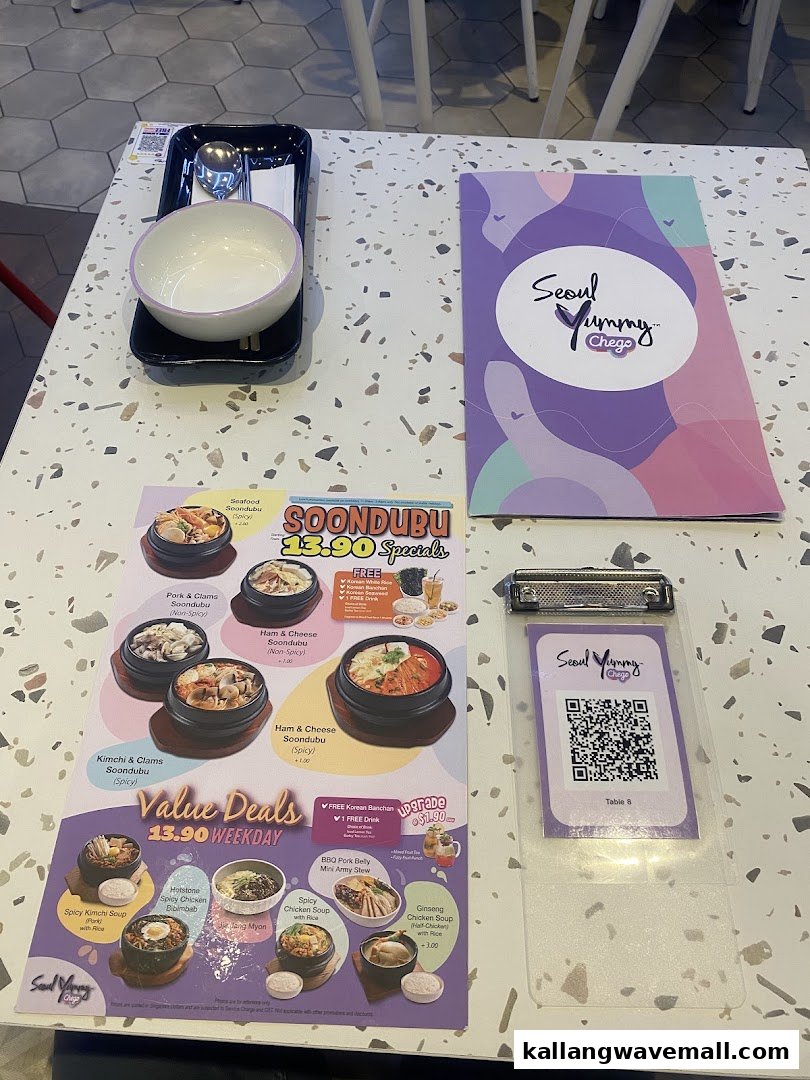 A table setting at Seoul Yummy Chego featuring a menu with Soondubu specials and weekday value deals.
