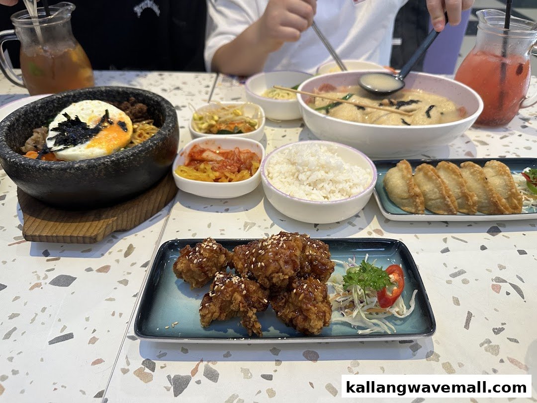 A table laden with various Korean dishes including bibimbap, fried chicken, and dumplings.