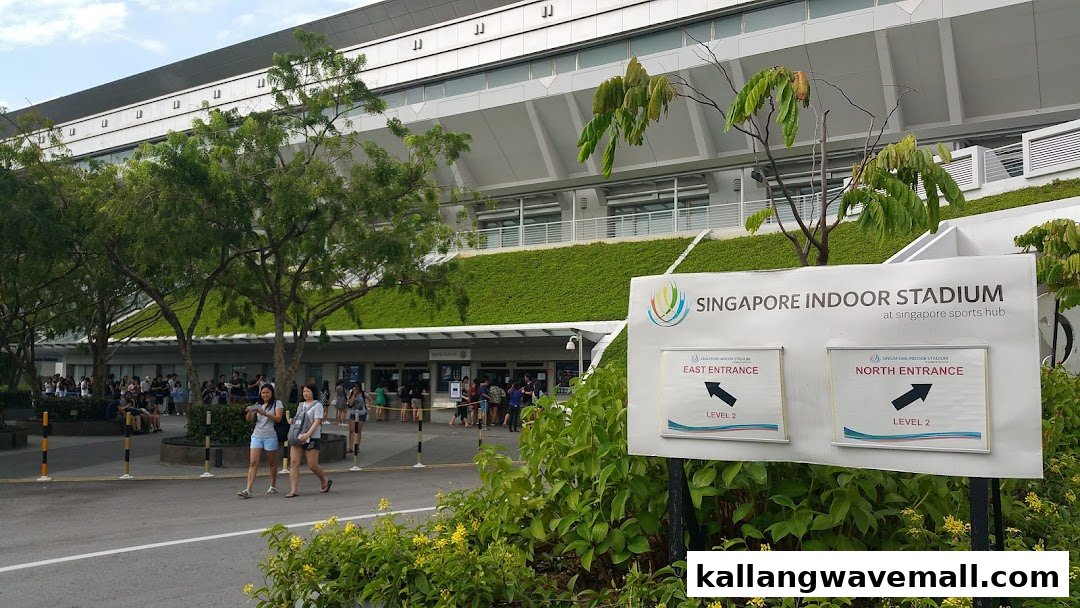 Exterior view of Singapore Indoor Stadium entrance with directional signs and people.