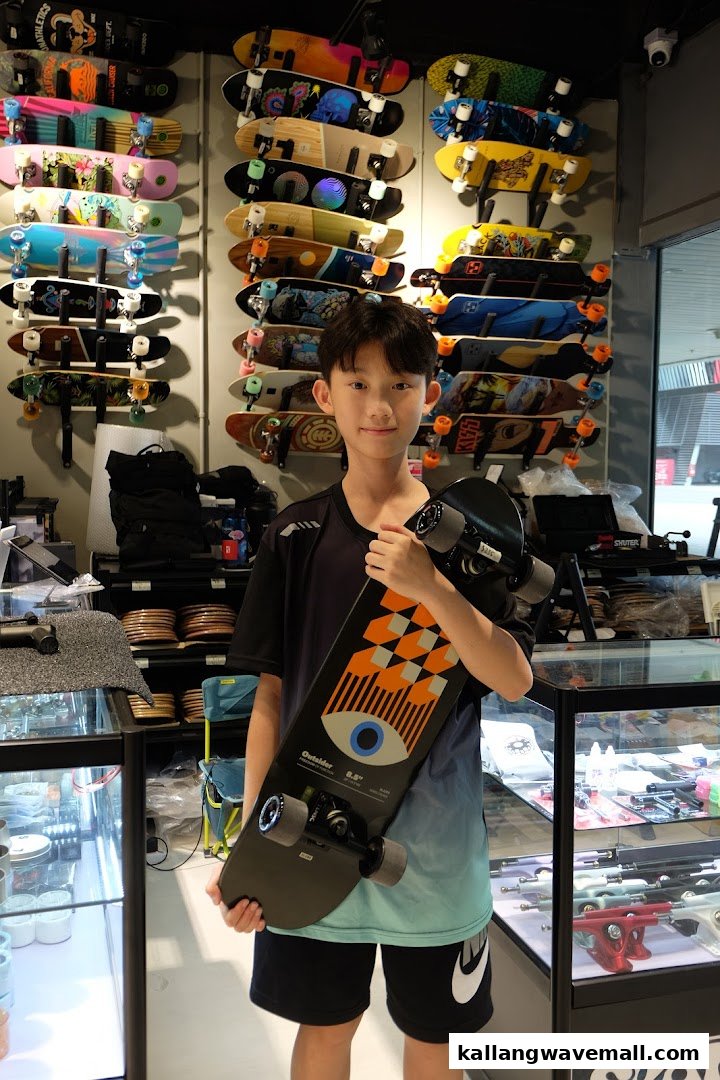 A young person holds a skateboard inside Skatebruh Skate Shop, surrounded by a vibrant display of skateboards.