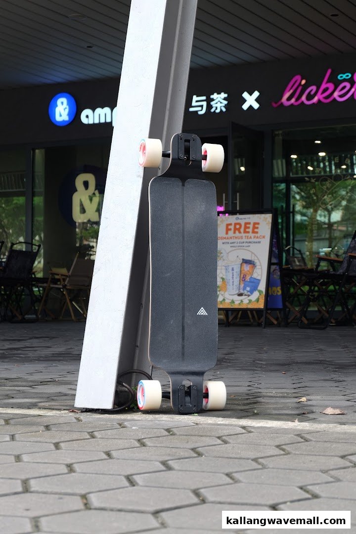 A sleek black longboard leans against a pillar outside a mall, showcasing skate culture.