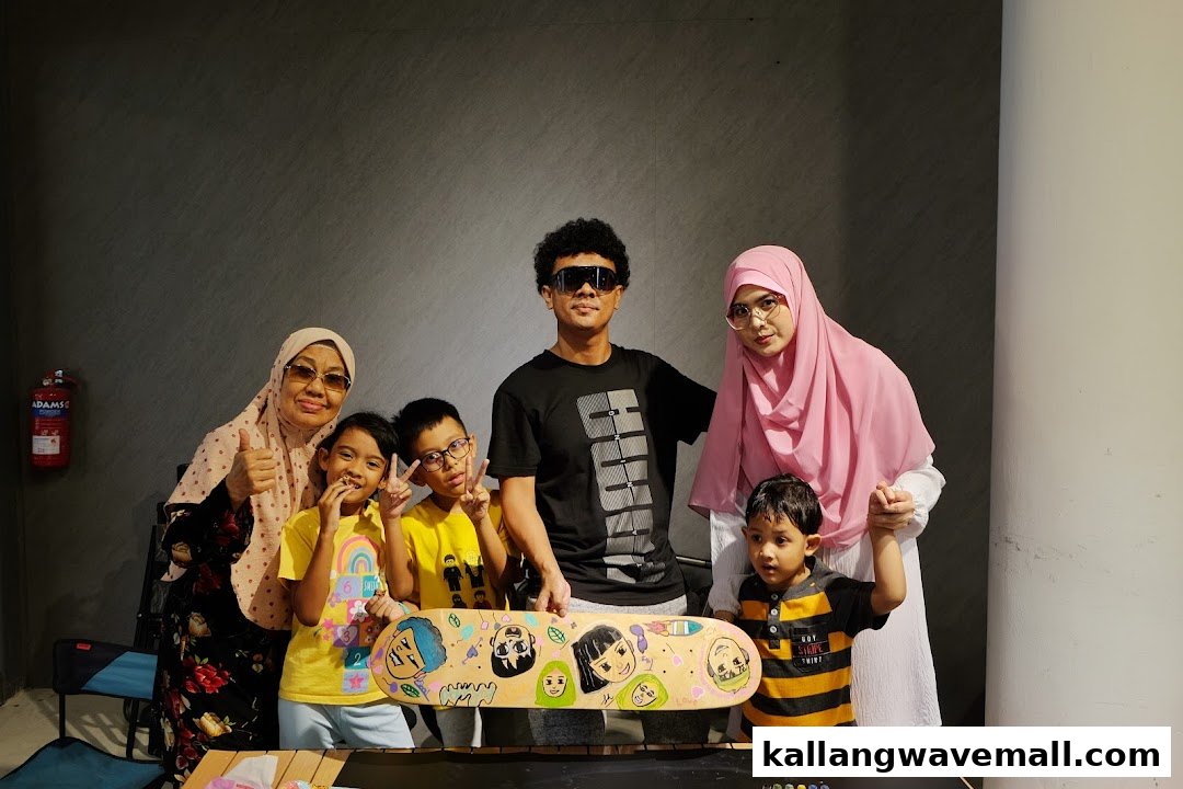 A group of people, including children and adults, proudly pose with a custom-painted skateboard.
