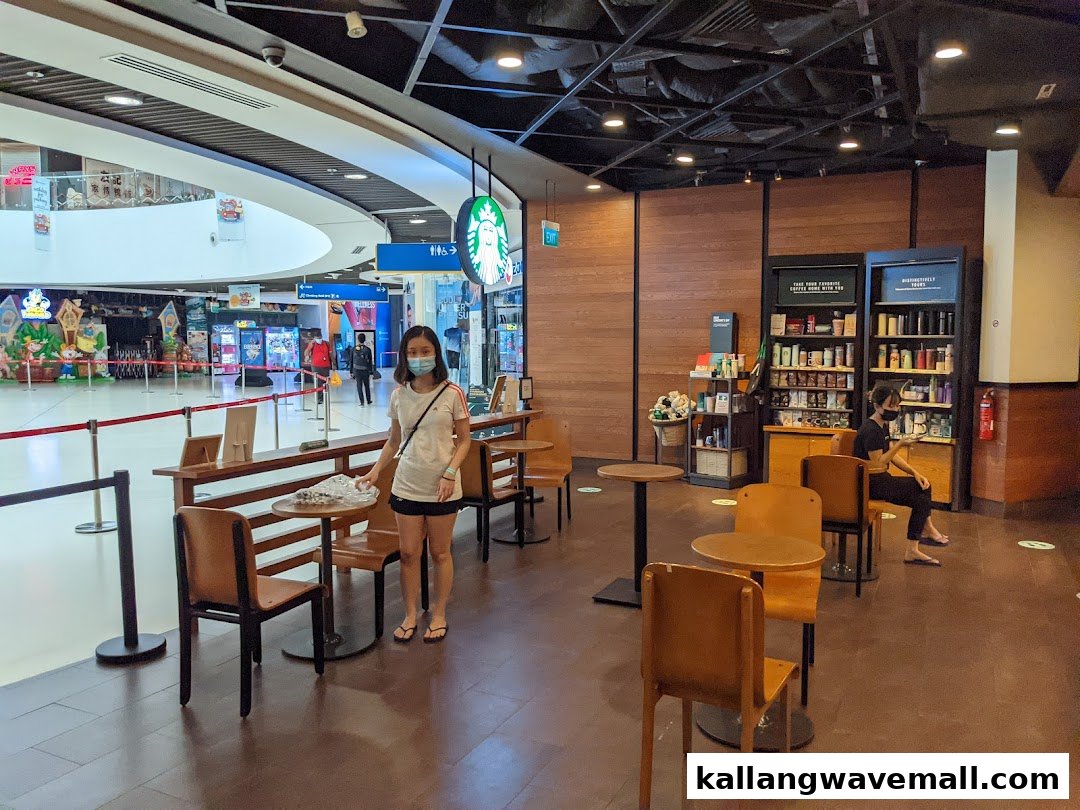 Interior view of Starbucks with seating, customers, and merchandise displays.