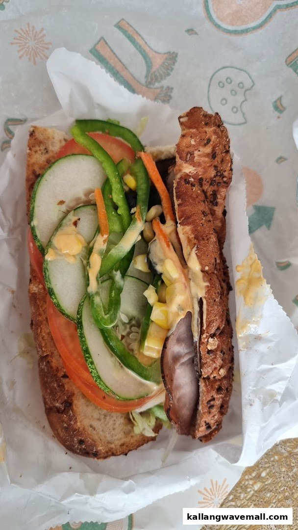A close-up of a fresh Subway sandwich filled with various vegetables and meat.