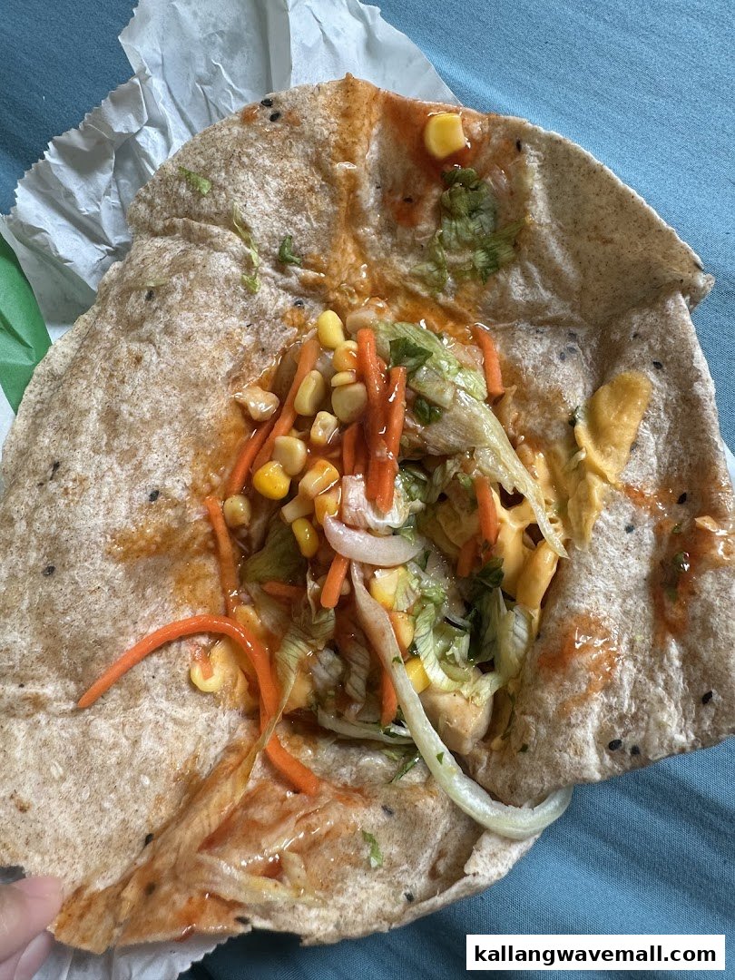A close-up of an unwrapped Subway wrap or flatbread filled with fresh vegetables and sauce.