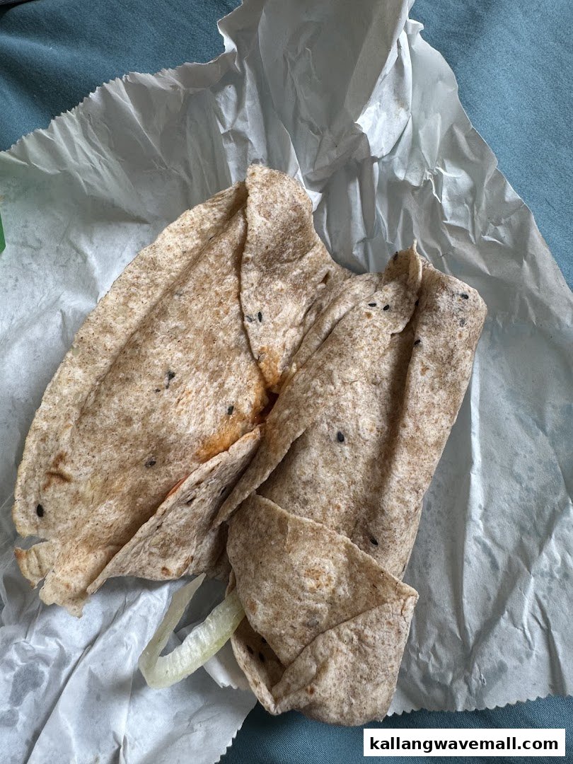 A close-up of a Subway wrap or flatbread sandwich, partially unwrapped, showing its texture and filling.