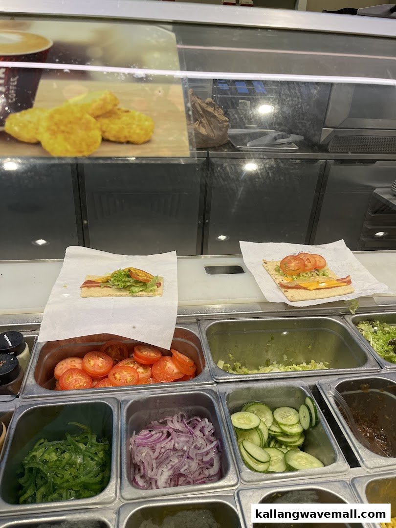 A vibrant view of Subway's fresh ingredients counter with various vegetables and two sandwiches being prepared.
