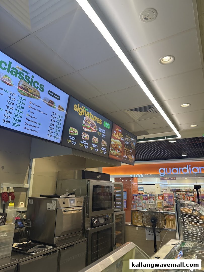Interior view of Subway showing digital menu boards, food preparation area, and kitchen equipment.