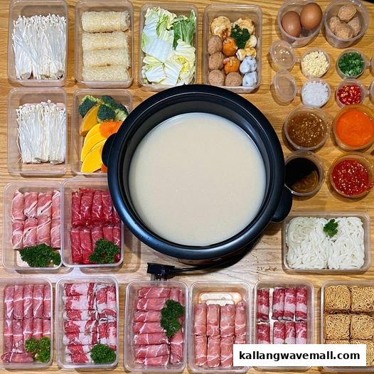 An overhead view of a shabu-shabu hot pot surrounded by various fresh ingredients like meats, vegetables, and sauces.