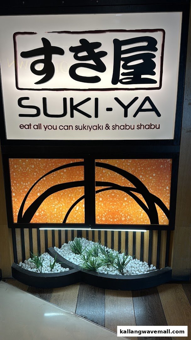 The illuminated Suki-Ya sign with Japanese characters, 'eat all you can sukiyaki & shabu shabu' text, and decorative planter.